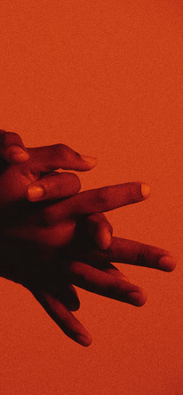 Overlapping hands lit in deep red against an orange background.