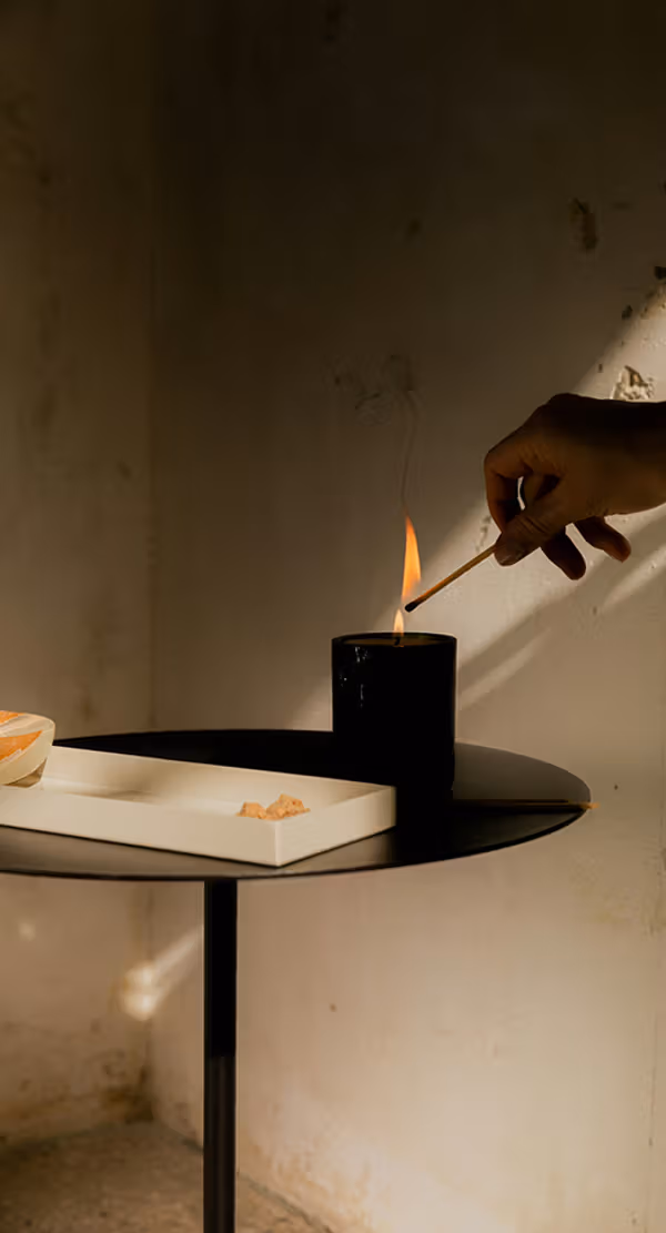 A hand lighting a candle on a round black table.